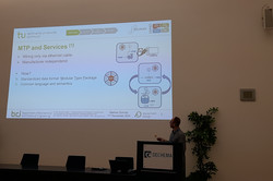 The image shows Mathias Schmitz during his talk at the PEMT.